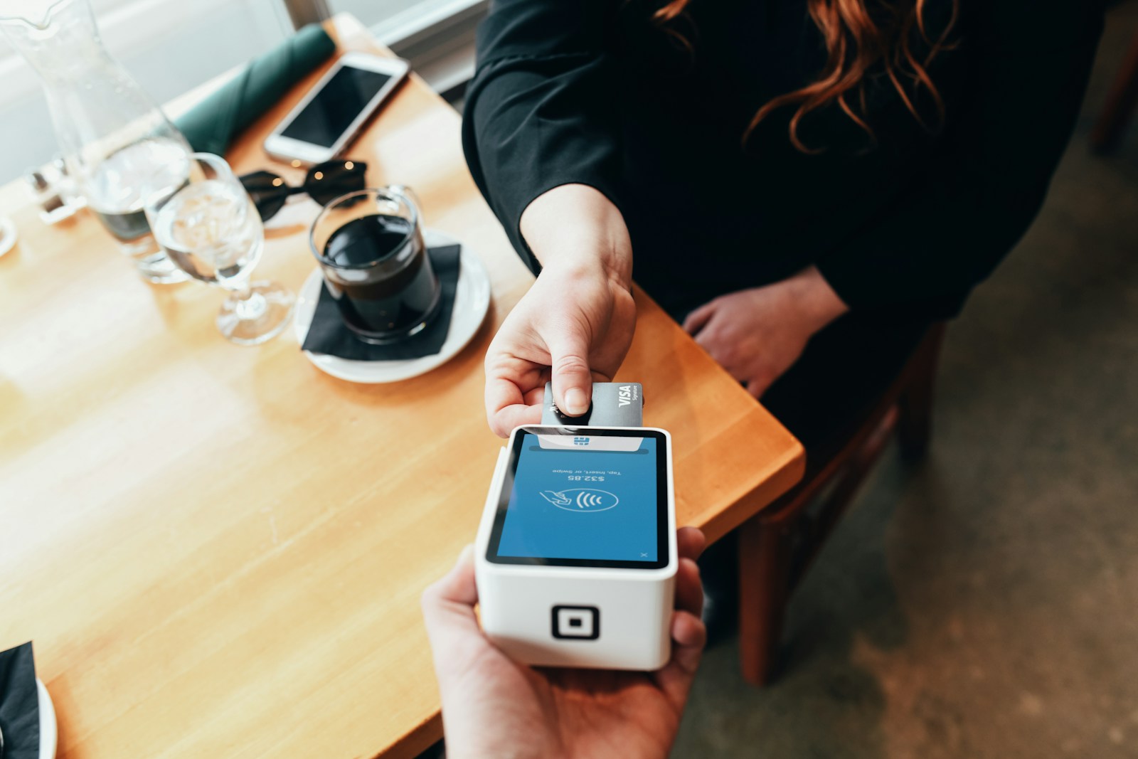 Person holding a modern credit card payment terminal device for secure electronic transactions in business environment